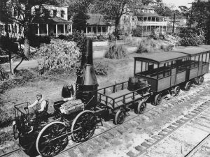 A black and white photo of the train Best Friend of Charleston on its rail tracks with residential homes in the background