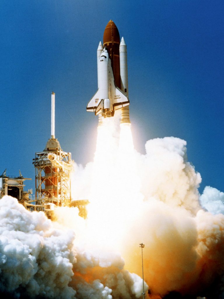The Space Shuttle Challenger lifting off from the launch pad at Kennedy Space Center