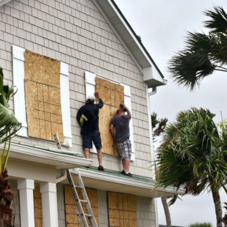 Workers boarding up windows on a home